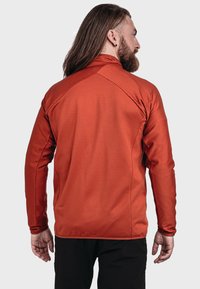 Langärmlige, taillierte Jacke aus geripptem, brennorangefarbenem Stoff mit hohem Kragen und kontrastierenden Nähten entlang der Schulternaht.