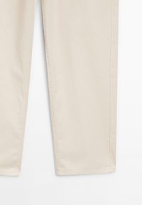 Pantalon beige à jambes droites avec coutures latérales apparentes et ourlets cousus sur un fond blanc uni.