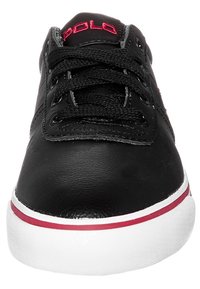 Zapatillas de cuero negras con logo rojo, suela blanca plana, cordones negros y acentos rojos en contraste en la suela. Diseño simple de punta redondeada.