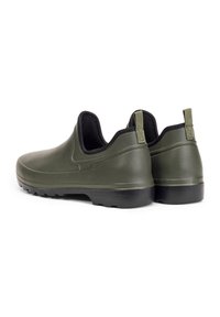 Chaussures en caoutchouc vertes à enfiler avec des bordures noires, présentant une surface texturée et des semelles noires plates. Onglets à l'arrière pour un enfilage facile.