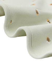 Lysegrønt stof med en blød tekstur, der har et mønster af små, stiliserede bier i gult og sort. Kanterne har en ribbet finish.