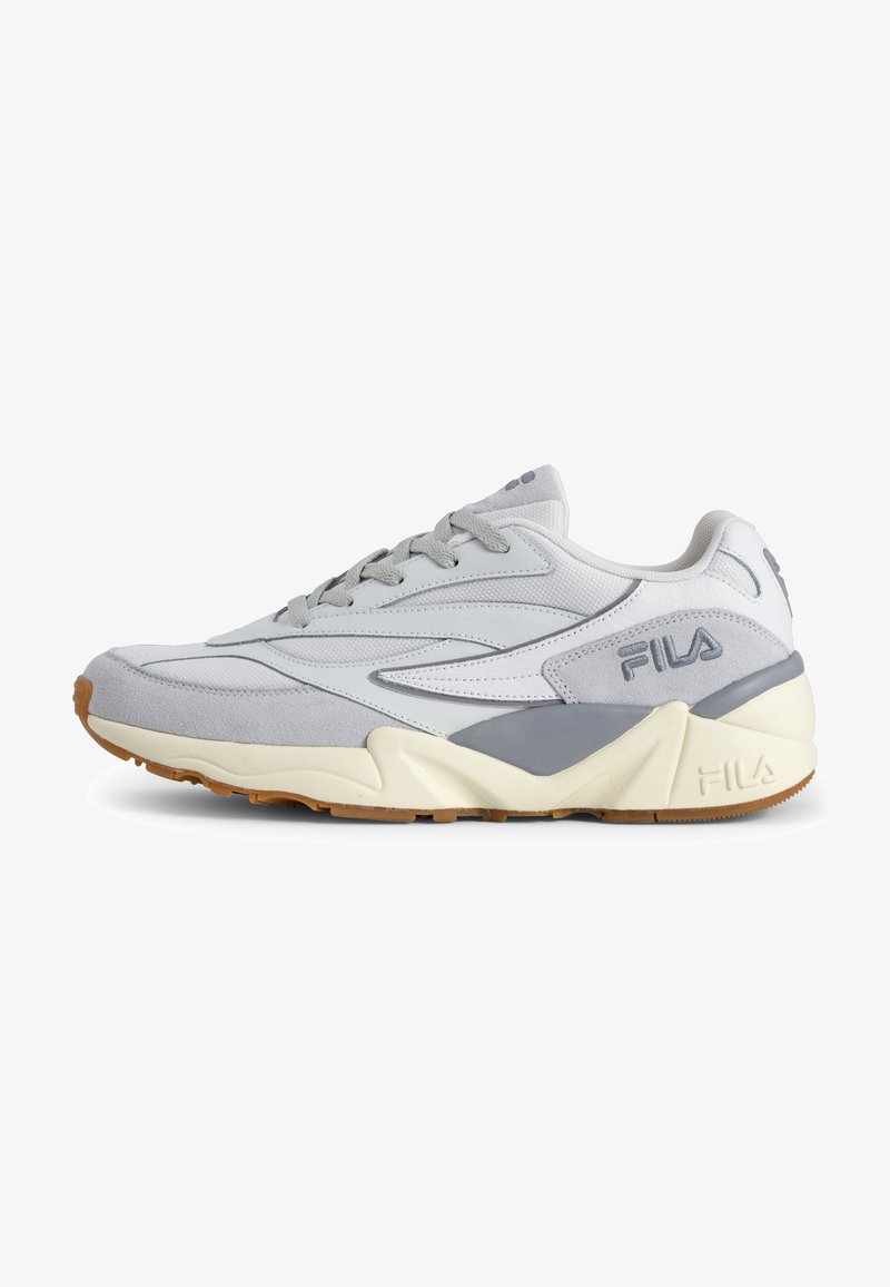 Grey athletic shoe featuring a mix of smooth and textured materials, lace-up design, and a contrasting gum rubber outsole. Fila branding displayed.