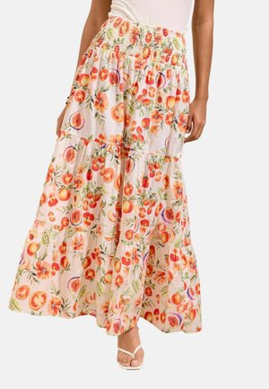 Jupe longue à volants avec taille élastique, présentant des motifs fruités et floraux éclatants en orange, rouge et vert sur tissu clair.