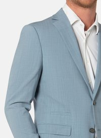 Vaaleansininen bleiseri, joka on valmistettu teksturoidusta kankaasta. Siinä on yksirivinen napitus, lovikaulus ja sivutasku. Valkoinen paita alla.