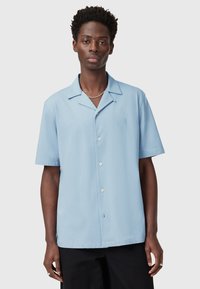 Camicia azzurra a maniche corte con colletto da campeggio, caratterizzata da un logo ricamato discreto e un tessuto leggero e morbido.