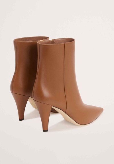 Brūni ādas potītes zābaki ar smailu purngalu un stiletto papēdi. Gluda tekstūra, minimālistisks dizains un sānu rāvējslēdzējs.