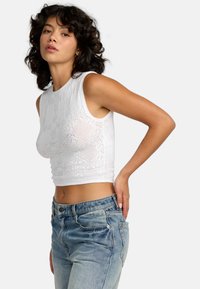 White knit crop top with a textured floral pattern, paired with high-waisted light blue jeans featuring a classic five-pocket design.