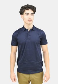 Polo navy con colletto, maniche corte e pattina con tre bottoni, realizzato in tessuto liscio, dalla forma aderente e dal design minimale.