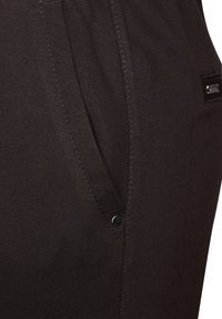 Braune Stoffhose mit glatter Textur, seitlicher Tasche mit schwarzem Knopfakzent und sichtbarem Nähdetail.