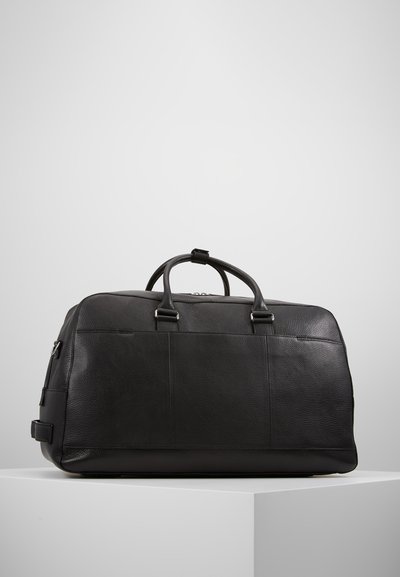 Geantă de duffel din piele neagră, cu mânere superioare duale, textură netedă și formă structurată. Dispune de accesorii din metal argintiu și un design minimalist.