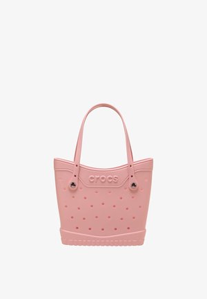 Roze Crocs-tas met ronde perforaties, twee schouderriemen en een getextureerde zoolachtige onderrand.