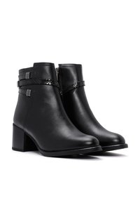 Bottines en cuir noir avec une finition lisse, ornées d'accents tressés et de détails en métal argenté. Design à talon carré pour la stabilité et le confort.
