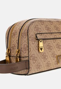 Brązowa kosmetyczka w wzory z zamkami błyskawicznymi i metalowymi elementami w złotym kolorze, o prostokątnym kształcie, z dodatkami ze skóry i detalem z logo.