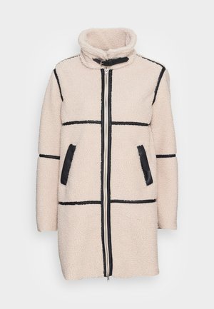 Lažni krzneni kaput u svijetlosmeđoj boji s crnim detaljima, visokim ovratnikom, prednjim zatvaračem i bočnim džepovima s teksturiranom završnom obradom i dizajnom panela.