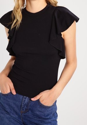 Sort ribbet top med korte flæseærmer, rund halsudskæring, tætsiddende design, kombineret med højtaljede blå denimjeans.