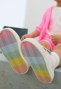 Tęczowe podeszwy sneakersów w pastelowych kolorach mają zygzakowaty wzór: różowy, fioletowy, niebieski, zielony, żółty i pomarańczowy. Białe gumowe krawędzie.