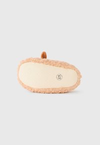 Myk beige bølgete teksturert babyslipper vist fra sålen, størrelse 25 merket, med en liten brun løkke på toppen.