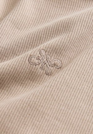 Beige räfflad tyg med en subtil struktur; har ett broderat dekorativt mönster i en matchande färg.