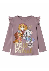 Fioletowa koszula z długim rękawem z falbaniastymi akcentami na ramionach oraz grafiką trzech kreskówkowych psów, z napisem "PAW Patrol" poniżej w złotym kolorze.