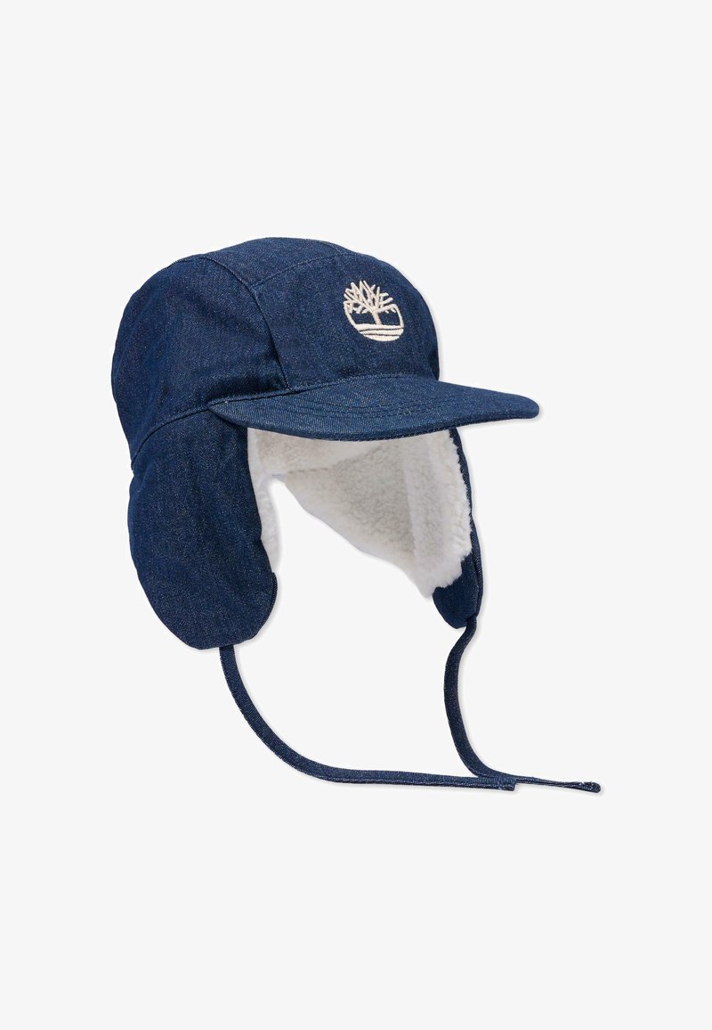 Jeansowa czapka z okrągłym daszkiem, nausznikami wyłożonymi białym futerkiem oraz haftowanym logo drzewa z przodu. Regulowane sznurki.