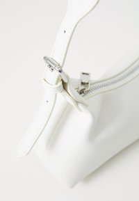 Borsa a tracolla in pelle bianca con chiusura a zip, caratterizzata da una texture liscia e una regolazione della tracolla in metallo argentato. Design compatto e moderno.