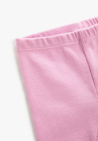 Jasnoróżowe legginsy z prążkowanej tkaniny, z elastyczną talią, charakteryzujące się miękką fakturą i gładkim wykończeniem. Materiał ma widoczne poziome linie.