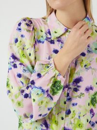 Blusa floral com fundo rosa e flores verdes e azuis, tecido leve, gola e punhos elásticos.