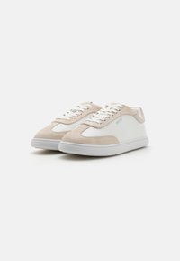Sneaker bianchi e beige con materiali in suede e pelle, caratterizzati da una punta tonda, chiusura con lacci e una suola in gomma texture.