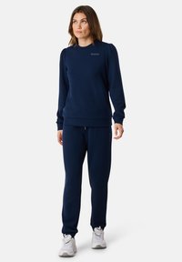 Felpa blu navy con dettagli testurizzati sulle spalle e stampa "SEASIDE", abbinata a pantaloni coordinati. Entrambi realizzati in materiale morbido.