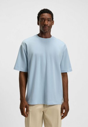Light blue short-sleeved t-shirt in soft fabric, featuring a round neck and relaxed fit. Smooth texture; no patterns or logos visible.