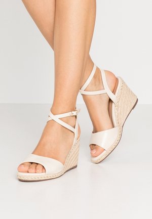 Beige wedge sandaalit, joissa on avonainen varvas, sileä nahkapinta, ristiin menevät nilkkahihnat ja kudottu juteeraus korossa.