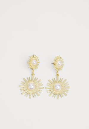 Gold-tone earrings featuring a sunburst design with textured rays, each centered with a white pearl. Dangle style with a stud base.