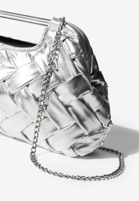 Hõbedane kootud käekott metallilise läikega, millel on palmikust kettrihm ja kortsus ülaosa, esitades sujuva, ümariku disaini.