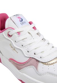 Sneaker bianca con accenti rosa e oro, dotata di un pannello in suede testurizzato, lacci piatti e un logo sulla linguetta.