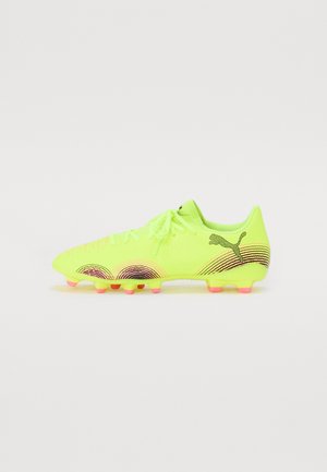 Scarpa da calcio gialla fluo con tomaia testurizzata, lacci piatti e accenti curvi neri e rosa sui lati. Tacchetti in TPU per trazione.