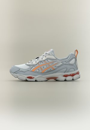 Grauer und weißer Sportschuh mit orangefarbenen Akzenten, Mesh- und synthetischen Materialien, Schnürdesign und gepolsterter Sohle mit strukturierter Profilierung.