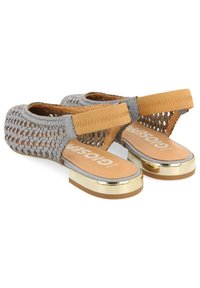 Zapatos grises trenzados con una banda elástica marrón claro, plantilla beige y un tacón de plataforma acentuado en dorado. Diseño de apertura en la parte trasera para mayor transpirabilidad.