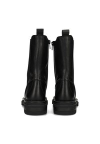 Botas de cuero negras hasta el tobillo con un acabado suave, detalles de costura prominentes, cremalleras laterales y suelas de goma planas.