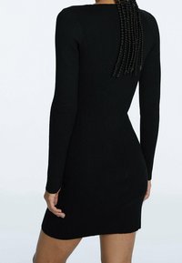 Schwarzes, geripptes Langarmkleid mit taillierter Silhouette, texturiertem Stoff und rundem Halsausschnitt. Oberschenkellange.