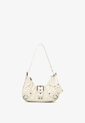 Kleine crèmekleurige leren schoudertas met gespsluiting, ritssluiting, verstelbare riem en aangehecht rechthoekig label op witte achtergrond.