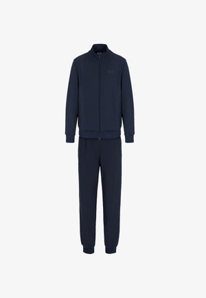 Tuta blu navy composto da una giacca con zip e colletto alto e pantaloni coordinati con polsini e vita elastici. Tessuto morbido.