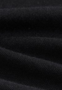 Gros plan sur une texture de tissu côtelé noir montrant un motif de tricot fin et des plis doux.