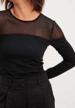 Maglietta nera a maniche lunghe con un pannello in rete trasparente sulle spalle e sul petto. Tessuto liscio con una silhouette aderente e scollatura rotonda.