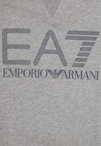 Grå sweatshirt med v-ringning som har stora marinblå "EA7 EMPORIO ARMANI"-texter och en distinkt logotyp. Mjuk, texturerad tyg.