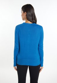Maglione blu a maniche lunghe con scollatura rotonda e orlo a coste. Tessuto liscio con una forma aderente, mostrato da dietro.