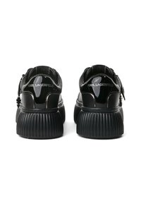 Mustast patendnahast sneakersid ribatud tallaga ja jämeda disainiga. Omavad brändingut kandadel ja metallaktsente paeladel.