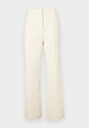 Calças de cor creme com um design de perna larga, cintura elástica e costuras laterais subtis. Apresenta um pequeno logotipo na parte inferior da frente.