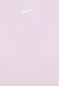 Tessuto rosa chiaro con piccole perforazioni e un logo bianco Nike swoosh centrato vicino alla parte superiore.