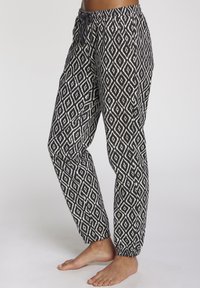Schwarz-weiße gemusterte Hose mit einem Diamantdesign, elastischem Bund mit Kordelzug und elastischen Bündchen an den Knöcheln.