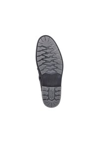 Suela de zapato de goma negra con un patrón texturizado que presenta surcos y protuberancias para mayor tracción. La zona del tacón tiene una marca grabada.